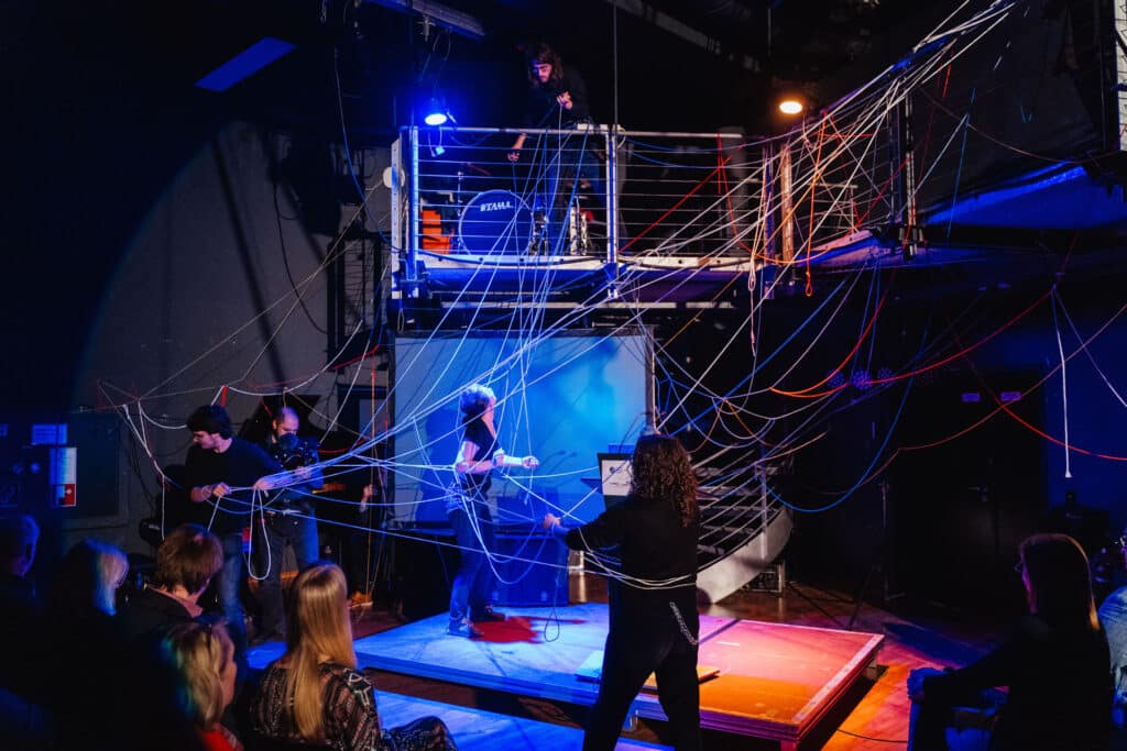 Theaterbühne mit Schauspieler:innen, die Fäden verwirren